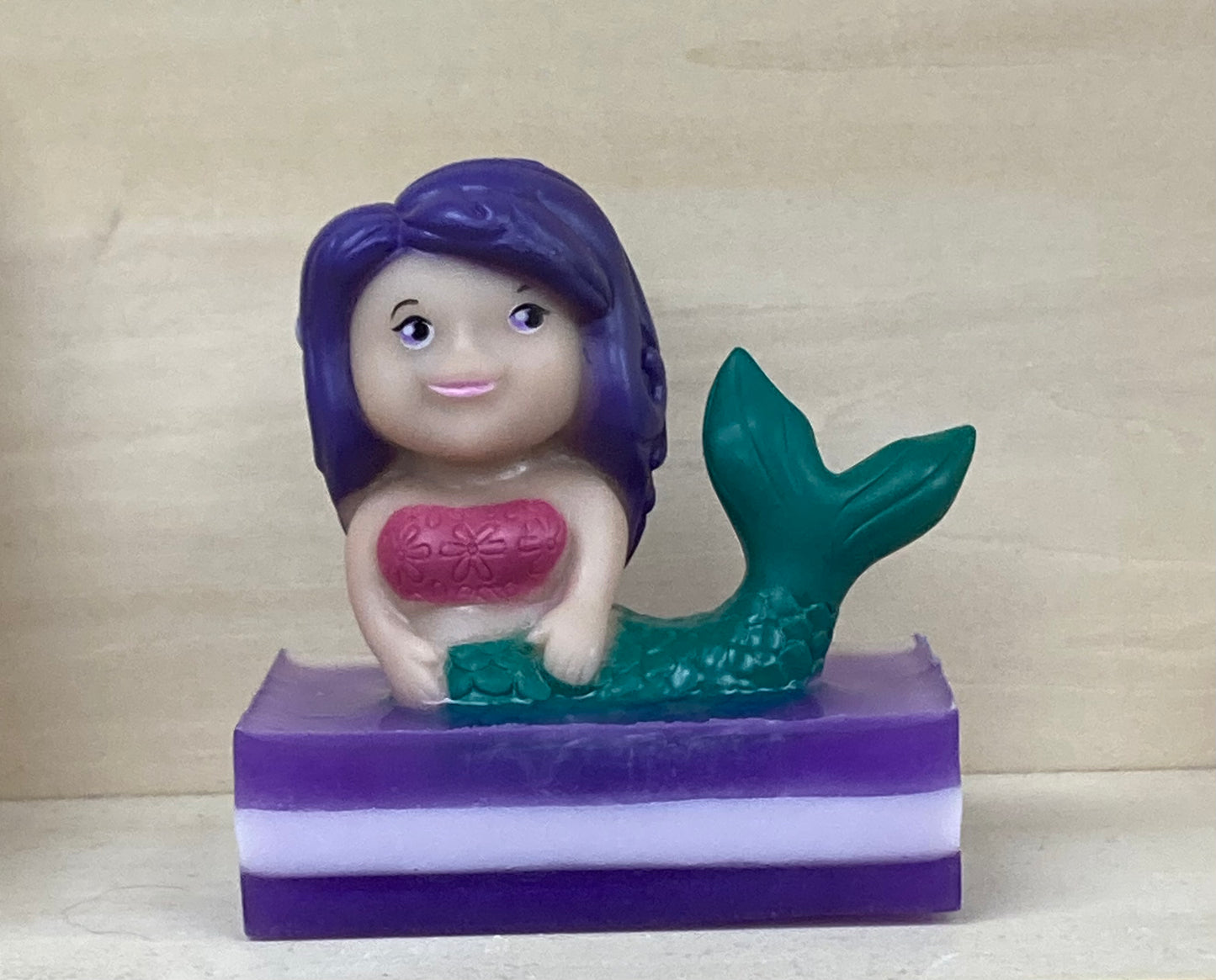 Make bath time magical with our Lydia the Mermaid Bath Buddy! A whimsical mermaid toy with vibrant purple hair perches gracefully atop a handcrafted bar of soothing shea butter and glycerin soap. Each Bath Buddy comes with its own story. Infused with a calming lavender scent, this delightful bath accessory is perfect for little mermaids, princesses, or anyone who loves a splash of fun and relaxation.