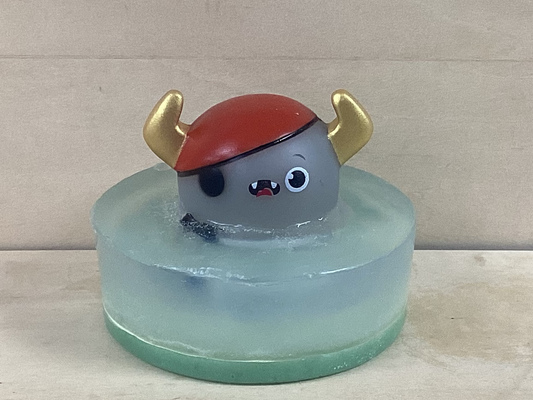 Toy figure with red helmet and gold horns on a clear base against a beige background