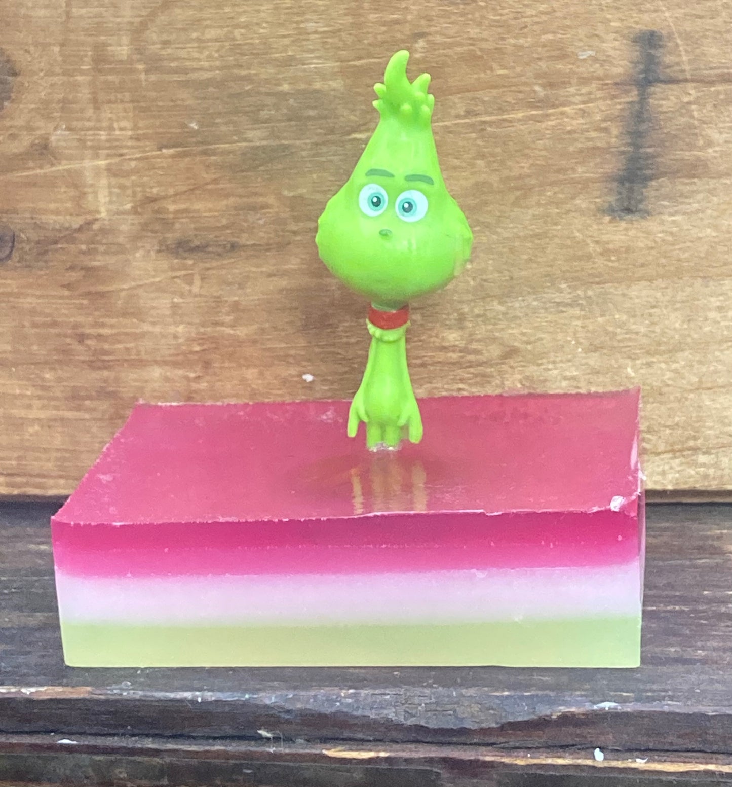 Small  Green Christmas Monster on top  of a bar of soap